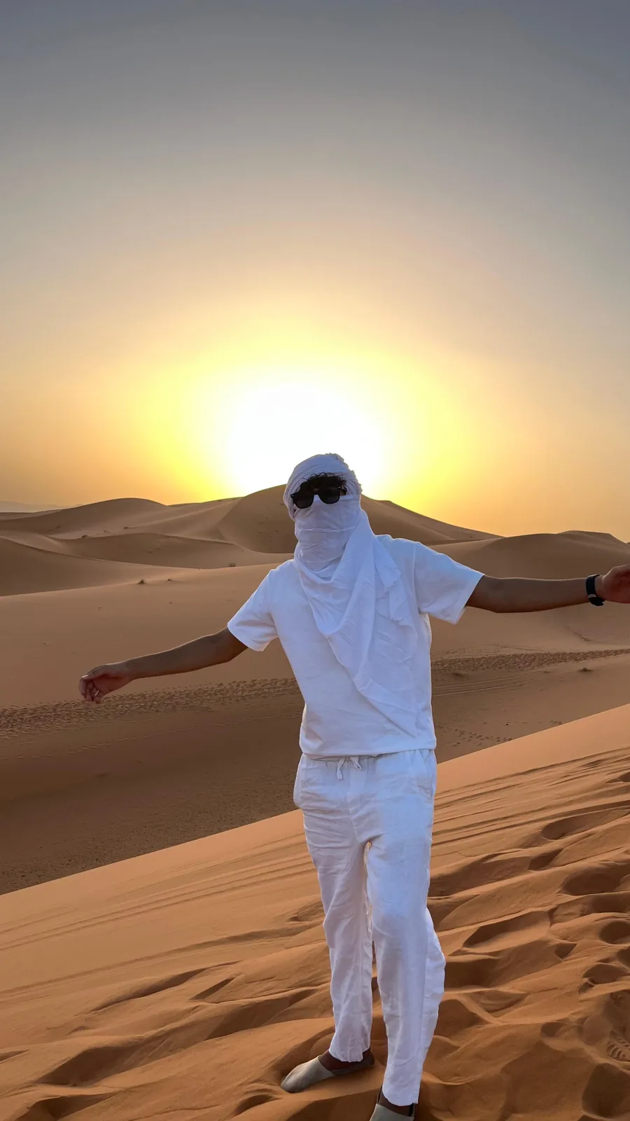 Viajero con los brazos abiertos al atardecer en el desierto