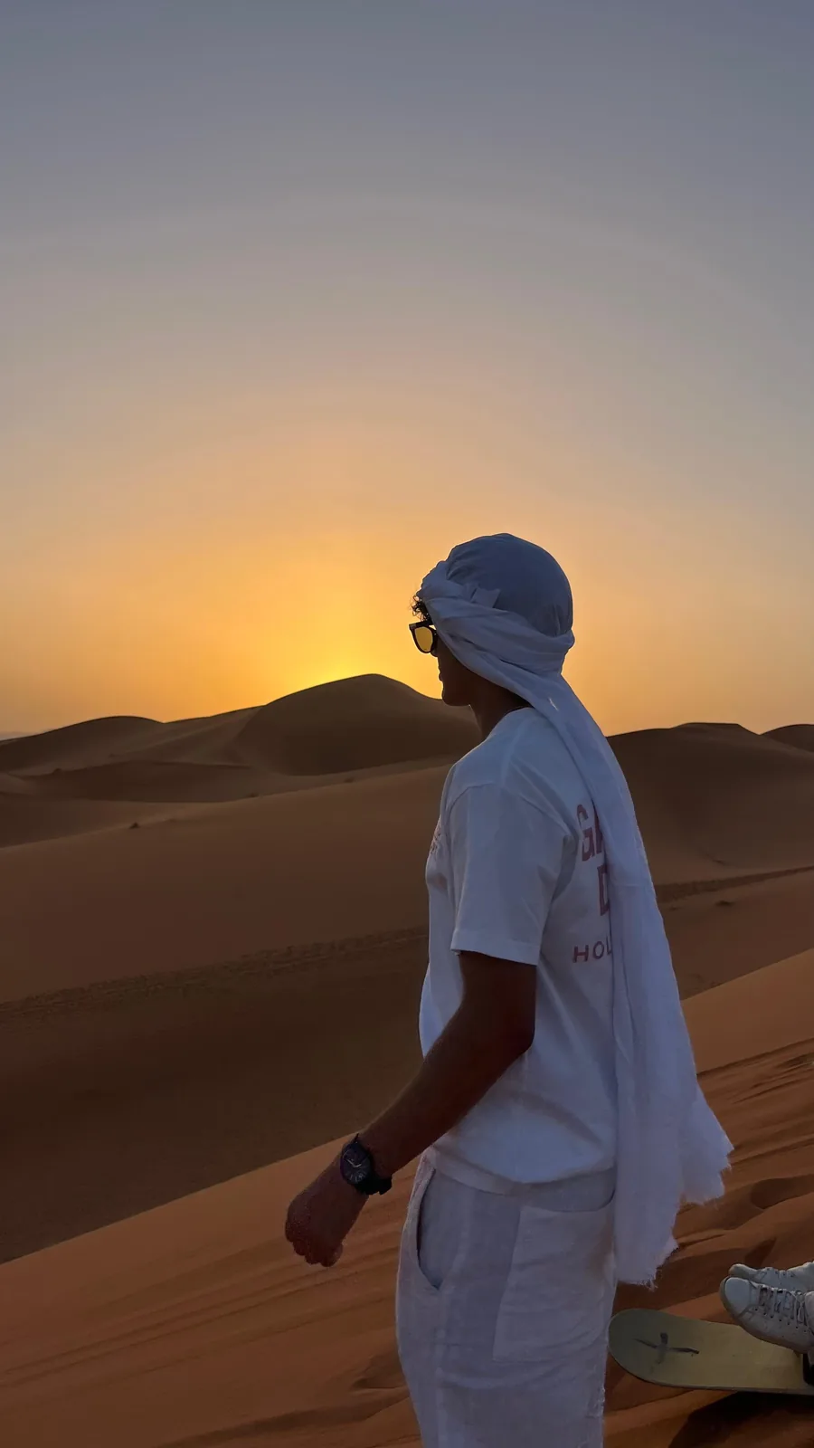 Viajero con turbante mirando el atardecer en las dunas